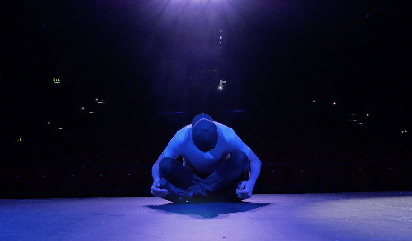 Crouched figure lit in blue